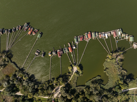 Aerial view of Bokodi Floating Village with colorful wooden houses on stilts connected by narrow walkways over the lake in Oroszlany Hungary. Aerial view of Bokodi Floating Village with colorful wooden houses on stilts connected by narrow walkways over the lake in Oroszlany Hungary.