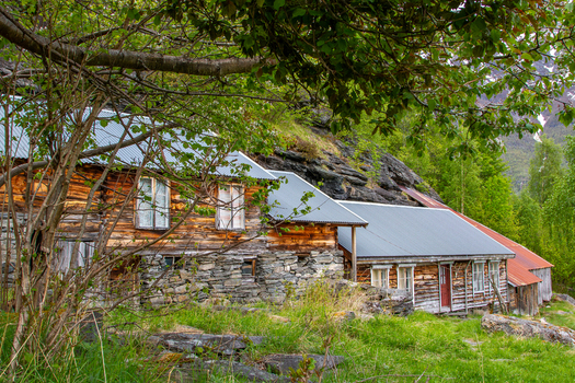 View of the historic Me Akneset mountain farm with traditional wooden buildings and stone foundations nestled in the lush green landscape of Stranda More og Romsdal Norway. View of the historic Me Akneset mountain farm with traditional wooden buildings and stone foundations nestled in the lush green landscape of Stranda More og Romsdal Norway.