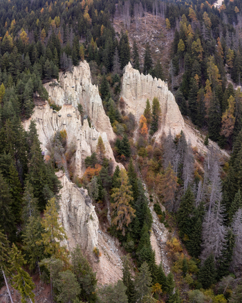 Aerial view of the Erdpyramiden Percha unique natural earth pyramids formed by erosion surrounded by dense coniferous forest and autumn foliage in Plata Trentino Alto Adige Italy.