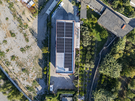 Aerial view of the Albamilk shpk facility with a large rooftop solar panel array surrounded by green trees and a paved parking area in Bahcallek Shkoder County Albania. Aerial view of the Albamilk shpk facility with a large rooftop solar panel array surrounded by green trees and a paved parking area in Bahcallek Shkoder County Albania.