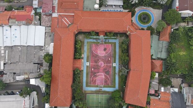 Aerial view of the Pondok Labu area featuring a U shaped building with red tile roofs surrounding a basketball court in Cilandak Jakarta Indonesia. Aerial view of the Pondok Labu area featuring a U shaped building with red tile roofs surrounding a basketball court in Cilandak Jakarta Indonesia.