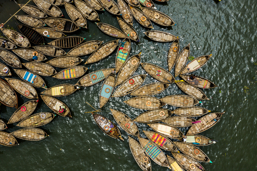Aerial view of numerous wooden boats docked closely together on the Buriganga River showcasing traditional transport vessels with colorful patterns in Dhaka Dhaka Division Bangladesh.