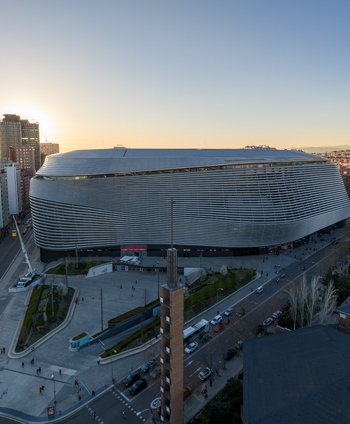 Aerial view of the Santiago Bernabeu stadium with its modern metallic facade surrounding urban streets and city buildings during the golden hour in Madrid Community of Madrid Spain. Aerial view of the Santiago Bernabeu stadium with its modern metallic facade surrounding urban streets and city buildings during the golden hour in Madrid Community of Madrid Spain.