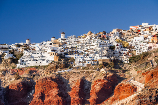 View of the white washed buildings and traditional windmills of Fira perched on the volcanic cliffs of Santorini Fira Greece. View of the white washed buildings and traditional windmills of Fira perched on the volcanic cliffs of Santorini Fira Greece.
