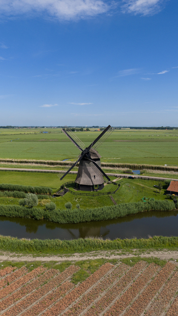 Aerial view of Bovenmolen G windmill surrounded by green fields a canal and agricultural land in Schermerhorn Noord Holland Netherlands. Aerial view of Bovenmolen G windmill surrounded by green fields a canal and agricultural land in Schermerhorn Noord Holland Netherlands.