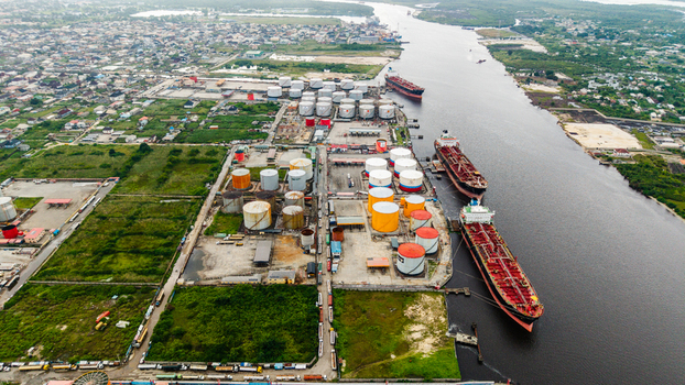 Aerial view of the industrial oil storage facility in Satellite Town with large storage tanks and cargo ships docked along the river in Lagos Lagos Nigeria.
