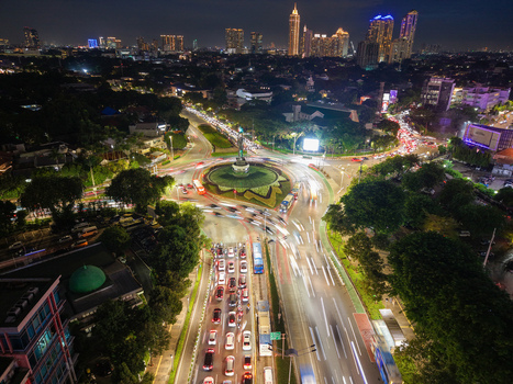 Aerial view of Patung Pemuda Membangun at the Senayan roundabout at night with light trails from traffic lush trees and the illuminated city skyline Kebayoran Baru Jakarta Indonesia. Aerial view of Patung Pemuda Membangun at the Senayan roundabout at night with light trails from traffic lush trees and the illuminated city skyline Kebayoran Baru Jakarta Indonesia.