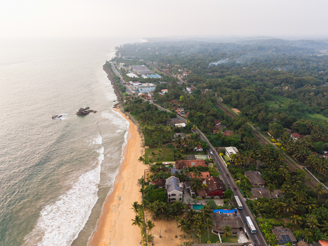 Aerial view of the tropical coastline with sandy beaches lush greenery and a coastal road in Galle Southern Province Sri Lanka.