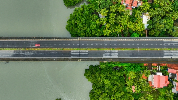 Aerial view of a bridge crossing a river surrounded by lush tropical palm trees and residential houses in Canacona Goa India.