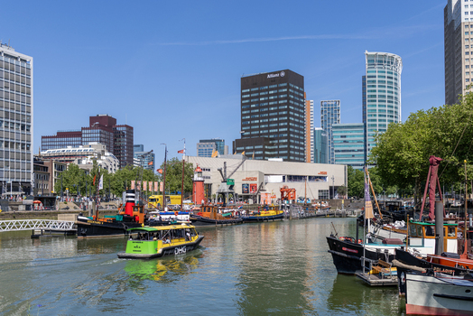 View of historic ships and a green water taxi at the Maritime Museum harbor in Leuvehaven with modern skyscrapers in the background Rotterdam South Holland Netherlands. View of historic ships and a green water taxi at the Maritime Museum harbor in Leuvehaven with modern skyscrapers in the background Rotterdam South Holland Netherlands.