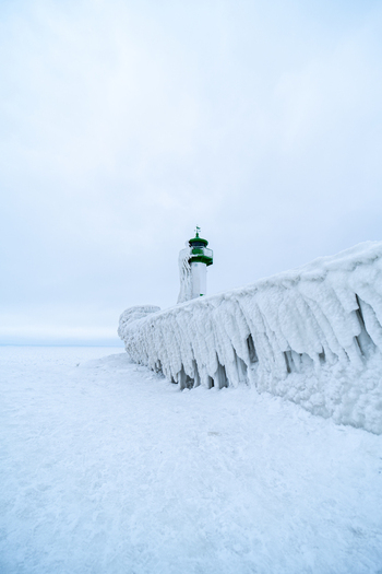 View of Molenfeuer Sassnitz lighthouse covered in thick ice and snow on a frozen pier during a cold winter day in Sassnitz Mecklenburg Vorpommern Germany.