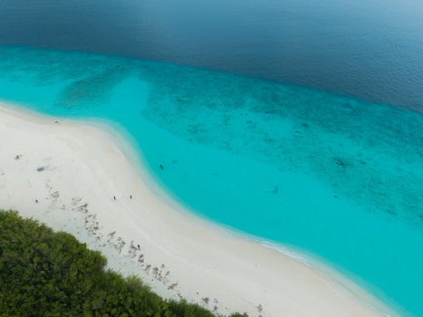 Aerial view of a white sand beach vibrant turquoise waters and deep blue ocean bordered by green trees Hoarafushi Thiladhunmathee Uthuruburi Maldives. Aerial view of a white sand beach vibrant turquoise waters and deep blue ocean bordered by green trees Hoarafushi Thiladhunmathee Uthuruburi Maldives.