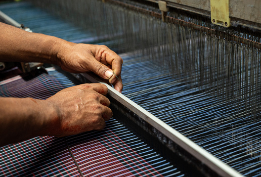 Joypurhat Rajshahi Division Bangladesh 22 September 2026 View of a skilled worker operating a mechanical loom to weave intricate blue and red fabric patterns. Joypurhat Rajshahi Division Bangladesh 22 September 2026 View of a skilled worker operating a mechanical loom to weave intricate blue and red fabric patterns.