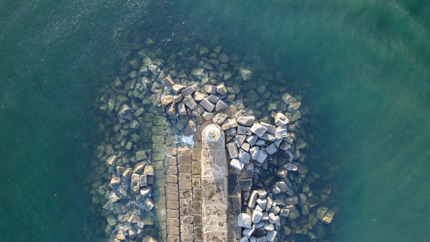 Aerial view of the Ferragudo lighthouse situated on a stone breakwater surrounded by calm turquoise sea water in Ferragudo Faro District Portugal.