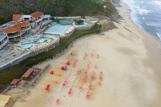 Aerial view of Praia de Sao Pedro de Moel with an abandoned building empty pools and colorful umbrellas on the sandy shore Marinha Grande Leiria Portugal. Aerial view of Praia de Sao Pedro de Moel with an abandoned building empty pools and colorful umbrellas on the sandy shore Marinha Grande Leiria Portugal.