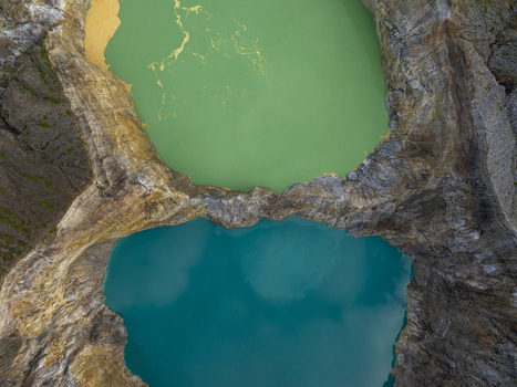 Aerial view of the vibrant green and turquoise crater lakes of Kelimutu National Park with rugged volcanic rock formations in Detusoko East Nusa Tenggara Indonesia.