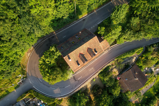 Aerial view of a sharp hairpin turn on a winding road passing by a historic house in Glion surrounded by dense green trees and lush vegetation in Montreux Vaud Switzerland. Aerial view of a sharp hairpin turn on a winding road passing by a historic house in Glion surrounded by dense green trees and lush vegetation in Montreux Vaud Switzerland.