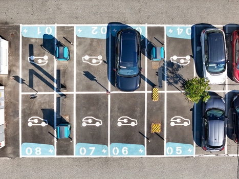 Aerial view of electric vehicle charging stations in a parking lot with numbered spots and parked cars under bright sunlight Turin Piedmont Italy. Aerial view of electric vehicle charging stations in a parking lot with numbered spots and parked cars under bright sunlight Turin Piedmont Italy.