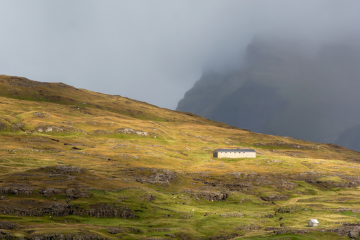 View of a remote building situated on a grassy hillside in the Faroe Islands.