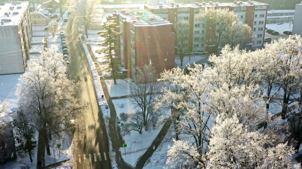 Aerial view of residential apartment buildings surrounded by snow covered trees and a quiet road in winter in Latvija. Aerial view of residential apartment buildings surrounded by snow covered trees and a quiet road in winter in Latvija.