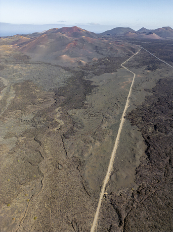 Aerial view of the volcanic landscape of Timanfaya National Park with rugged lava fields and distant craters in Lanzarote Canarias Spain. Aerial view of the volcanic landscape of Timanfaya National Park with rugged lava fields and distant craters in Lanzarote Canarias Spain.
