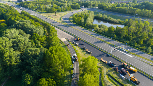 Waardenburg Netherlands 09 May 2026 Aerial view of roadwork and asphalt paving on a highway surrounded by lush green forests and a small pond. Waardenburg Netherlands 09 May 2026 Aerial view of roadwork and asphalt paving on a highway surrounded by lush green forests and a small pond.