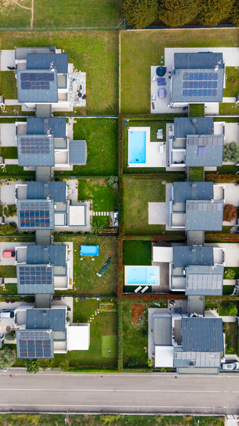 Aerial view of modern residential houses with solar panels private swimming pools and manicured green gardens in a suburban neighborhood Milan Lombardy Italy.