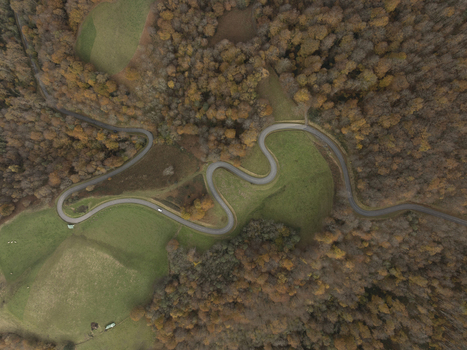Aerial view of a winding road through the autumn forest and green meadows in the Pyrenees Spain. Aerial view of a winding road through the autumn forest and green meadows in the Pyrenees Spain.