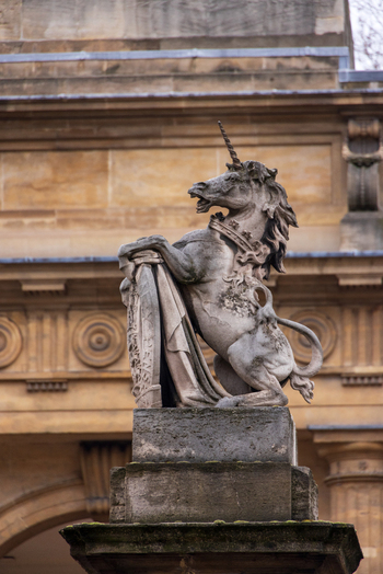 London United Kingdom 12 May 2025 View of a heraldic unicorn statue holding a shield in front of a classical building with columns and decorative stone carvings.