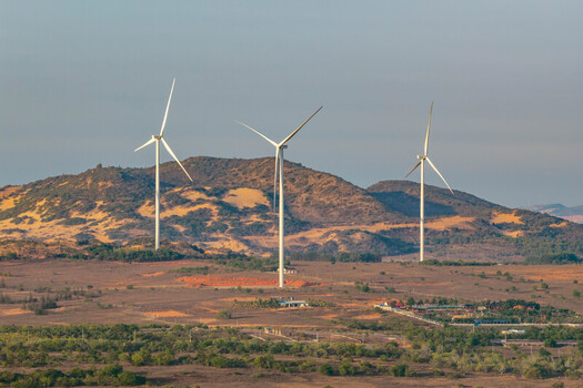 Aerial view of the Phuoc Dinh Wind Farm with large white wind turbines set against rolling arid hills and sparse vegetation in Phuoc Dinh Ninh Thuan Vietnam. Aerial view of the Phuoc Dinh Wind Farm with large white wind turbines set against rolling arid hills and sparse vegetation in Phuoc Dinh Ninh Thuan Vietnam.