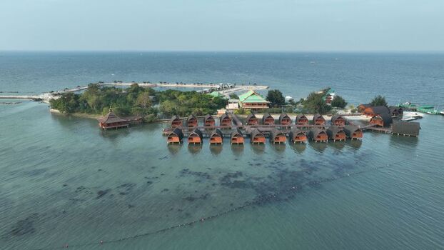 Aerial view of Pulau Lima Resort featuring wooden overwater bungalows lush greenery and clear turquoise waters in Kasemen Banten Indonesia. Aerial view of Pulau Lima Resort featuring wooden overwater bungalows lush greenery and clear turquoise waters in Kasemen Banten Indonesia.