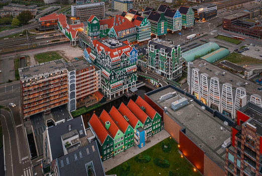 Zaandam Netherlands 26 April 2022 Aerial view of Inntel Hotels Amsterdam Zaandam with its unique stacked green house facade surrounding modern architecture and urban streets at dusk.