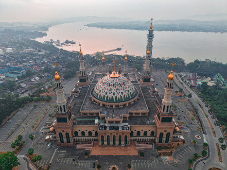 Aerial view of the Baitul Muttaqien Mosque with its large patterned dome and minarets situated near the Mahakam River in Samarinda East Kalimantan Indonesia.