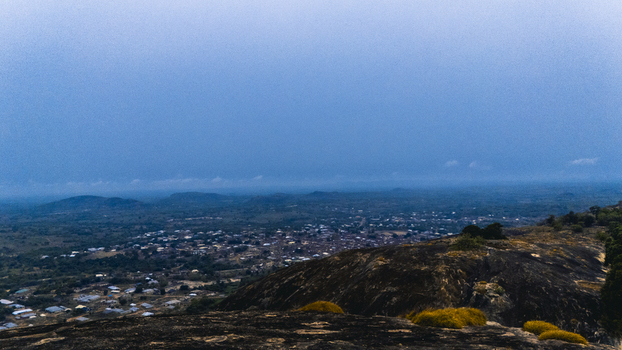 Aerial view of rolling hills meeting the horizon under a vast sky with the town nestled below a tapestry of rooftops and roads Oyo Oyo Nigeria. Aerial view of rolling hills meeting the horizon under a vast sky with the town nestled below a tapestry of rooftops and roads Oyo Oyo Nigeria.