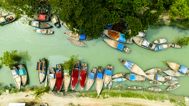 Aerial view of numerous wooden boats moored along the riverbank in Patharghata Barisal Division Bangladesh. Aerial view of numerous wooden boats moored along the riverbank in Patharghata Barisal Division Bangladesh.