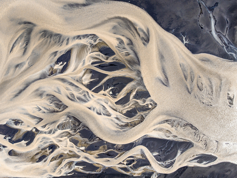 Aerial view of a complex braided river system with light colored sediment rich water flowing over dark volcanic sand in Iceland. Aerial view of a complex braided river system with light colored sediment rich water flowing over dark volcanic sand in Iceland.