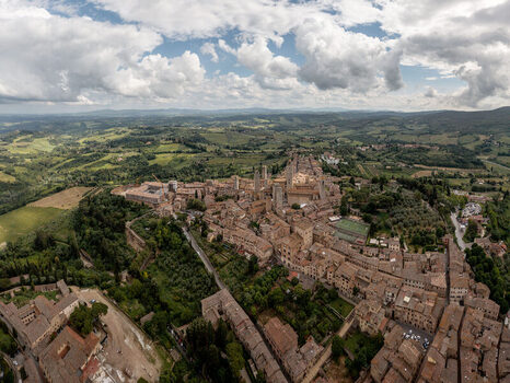 Aerial view of the historic town of San Gimignano with its iconic medieval towers surrounded by the rolling hills and lush landscape of San Gimignano Tuscany Italy. Aerial view of the historic town of San Gimignano with its iconic medieval towers surrounded by the rolling hills and lush landscape of San Gimignano Tuscany Italy.