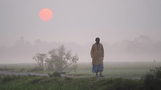 View of a man walking in a foggy field at sunrise Bangladesh. View of a man walking in a foggy field at sunrise Bangladesh.