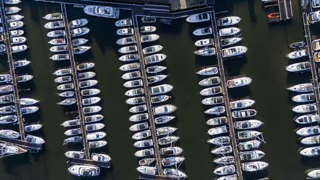 Aerial view of numerous white boats neatly docked in a marina creating a mesmerizing grid pattern against the dark water Southampton England United Kingdom. Aerial view of numerous white boats neatly docked in a marina creating a mesmerizing grid pattern against the dark water Southampton England United Kingdom.