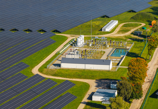 Aerial view of a large solar farm with rows of photovoltaic panels and a central electrical substation surrounded by green fields in Pomeranian Voivodeshi Poland. Aerial view of a large solar farm with rows of photovoltaic panels and a central electrical substation surrounded by green fields in Pomeranian Voivodeshi Poland.