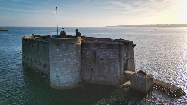 Aerial view of Chateau du Taureau stone fortress standing majestically in the sea the water reflecting the soft sunlight creating a serene yet formidable vista Plouezoc h Bretagne France. Aerial view of Chateau du Taureau stone fortress standing majestically in the sea the water reflecting the soft sunlight creating a serene yet formidable vista Plouezoc h Bretagne France.