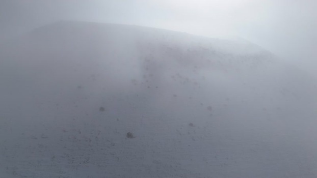 Aerial view of a snowy volcanic cone shrouded in thick fog Turkiye.