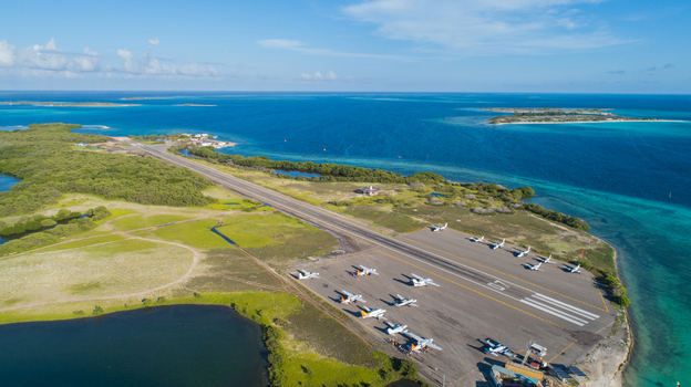 Aerial view of Los Roques airport with small aircraft on the tarmac surrounded by turquoise Caribbean waters and lush vegetation in Los Roques Dependencias Federales Venezuela. Aerial view of Los Roques airport with small aircraft on the tarmac surrounded by turquoise Caribbean waters and lush vegetation in Los Roques Dependencias Federales Venezuela.