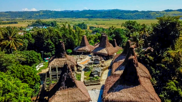Aerial view of Praijing Village with its traditional houses featuring high thatched roofs nestled among lush trees and rolling hills in Kota Walkabubak East Nusa Tenggara Indonesia. Aerial view of Praijing Village with its traditional houses featuring high thatched roofs nestled among lush trees and rolling hills in Kota Walkabubak East Nusa Tenggara Indonesia.
