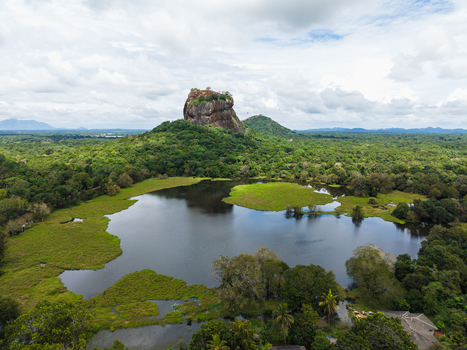Aerial view of Sigiriya Lion Rock rising above the lush green jungle and a calm lake under a cloudy sky in Sigiriya Central Province Sri Lanka. Aerial view of Sigiriya Lion Rock rising above the lush green jungle and a calm lake under a cloudy sky in Sigiriya Central Province Sri Lanka.