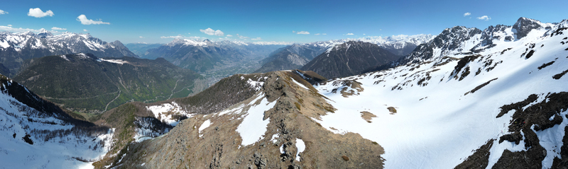 Aerial view of Pointe Ronde mountain peak with snow covered slopes rocky ridges and the distant Trient valley under a clear blue sky Trient Valais Switzerland.