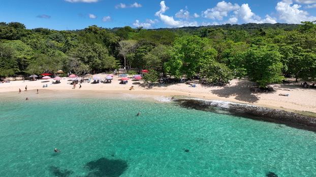 Aerial view of La Casita de Playa beach with turquoise water colorful umbrellas on the sand and lush green trees in Rio San Juan Maria Trinidad Sanchez Dominican Republic.