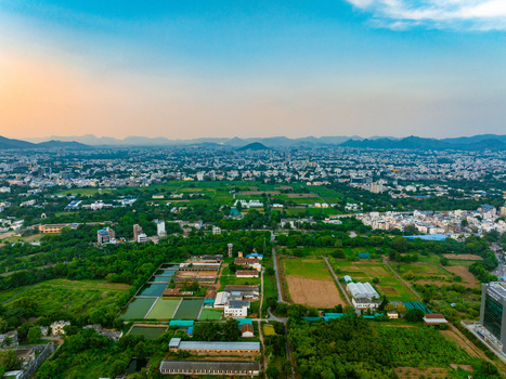 Aerial view of the cityscape of Udaipur with lush green fields agricultural ponds and residential buildings in Udaipur Rajasthan India. Aerial view of the cityscape of Udaipur with lush green fields agricultural ponds and residential buildings in Udaipur Rajasthan India.