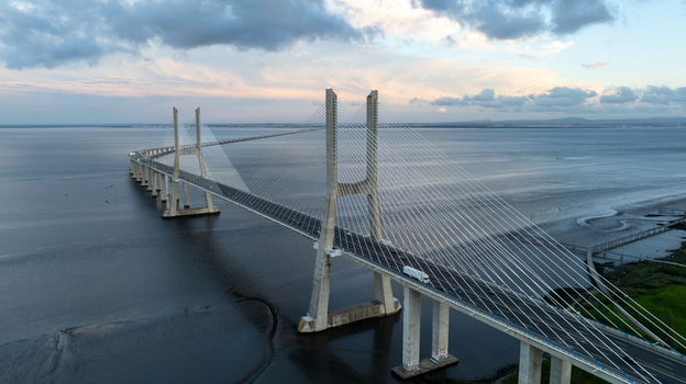 Aerial view of the Vasco da Gama Bridge spanning the Tagus River with traffic and cloudy skies in Lisboa Portugal.