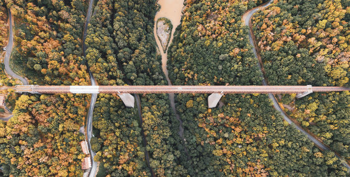 Aerial view of the historic Fades viaduct spanning the Sioule river surrounded by dense autumn forests and winding roads in Les Ancizes Comps Auvergne Rhone Alpes France. Aerial view of the historic Fades viaduct spanning the Sioule river surrounded by dense autumn forests and winding roads in Les Ancizes Comps Auvergne Rhone Alpes France.